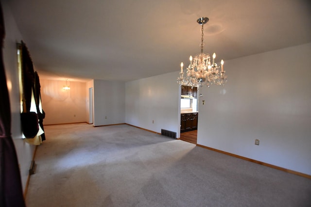 carpeted empty room featuring an inviting chandelier