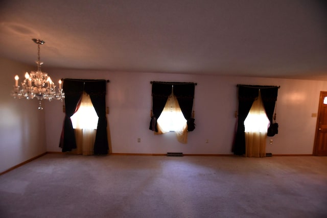 carpeted empty room with an inviting chandelier