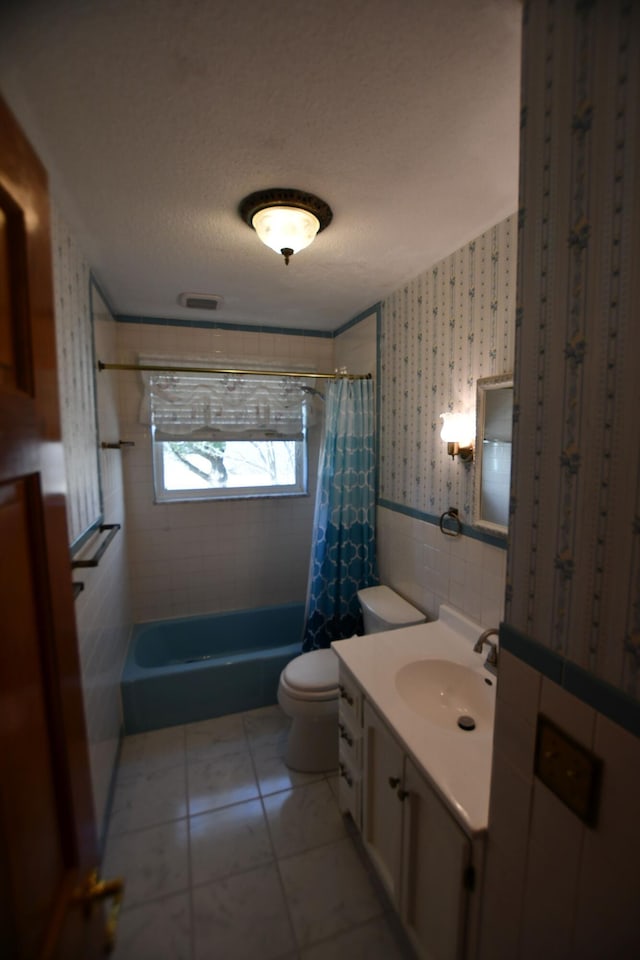 full bathroom featuring tile walls, tile patterned flooring, shower / tub combo, vanity, and a textured ceiling