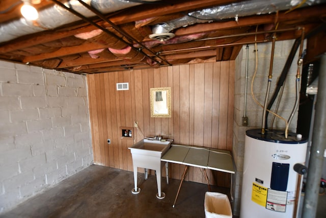 recreation room with concrete floors, electric water heater, and wood walls