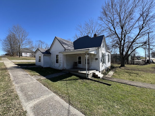 view of front of house featuring a front yard, metal roof, and a chimney