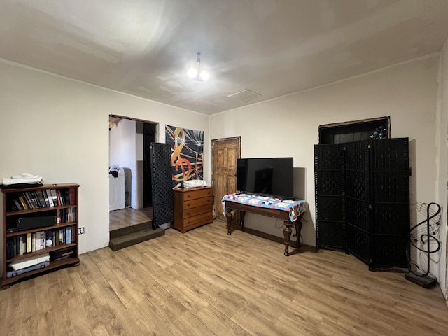 bedroom with washer / dryer and light hardwood / wood-style floors