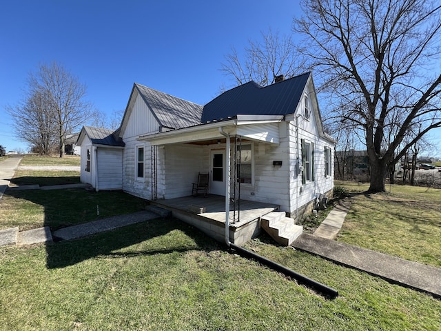 view of side of property featuring metal roof, a lawn, and a chimney