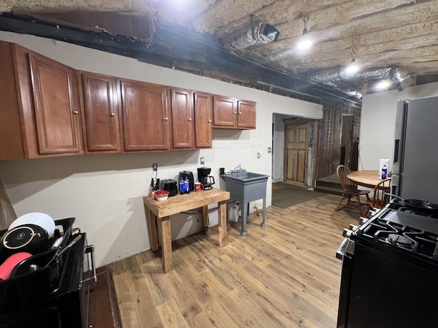 kitchen featuring light hardwood / wood-style floors, stainless steel refrigerator, and black gas stove