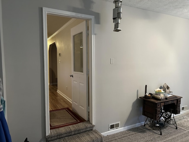 hallway with hardwood / wood-style floors, crown molding, and a textured ceiling