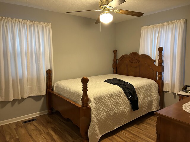 bedroom featuring wood-type flooring, a textured ceiling, and ceiling fan