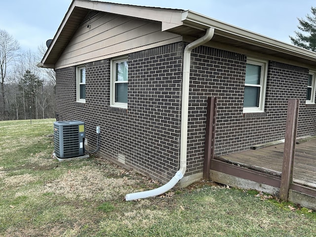 view of side of property with a wooden deck, central AC, and a lawn