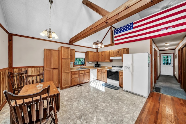 kitchen with white appliances, vaulted ceiling with beams, an inviting chandelier, under cabinet range hood, and a sink