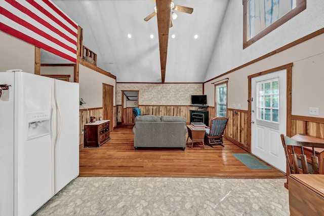 living room featuring wainscoting, ceiling fan, wood finished floors, a fireplace, and high vaulted ceiling