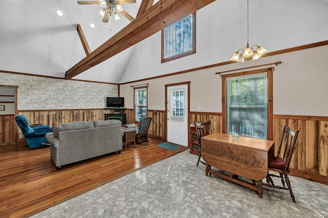 living area with a wainscoted wall, wood-type flooring, beam ceiling, and a wealth of natural light