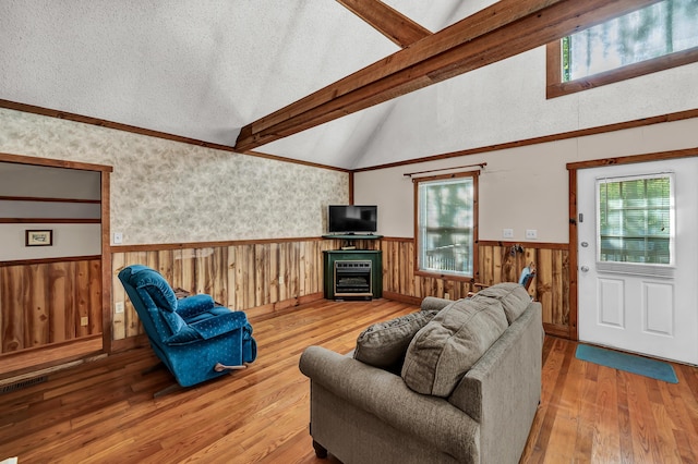 living room with vaulted ceiling with beams, wood-type flooring, visible vents, wainscoting, and a textured ceiling