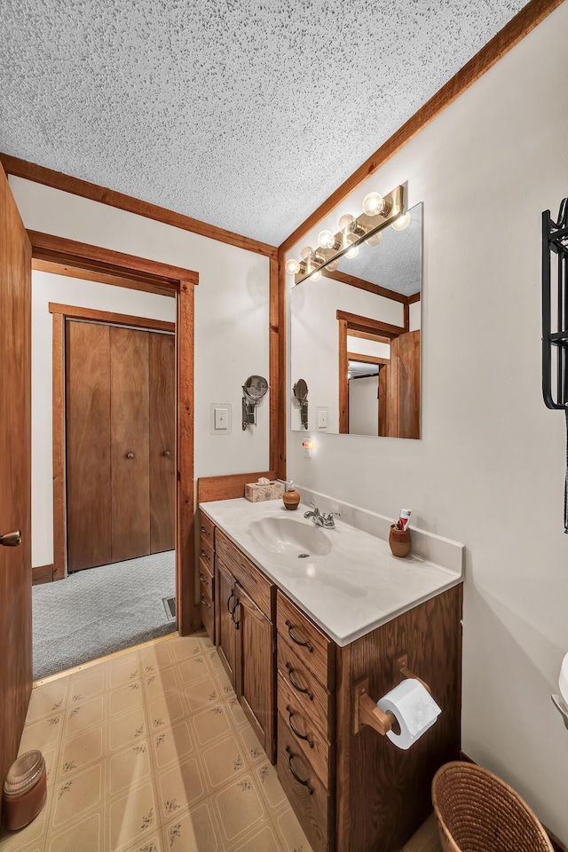 bathroom with ornamental molding, a textured ceiling, vanity, and tile patterned floors