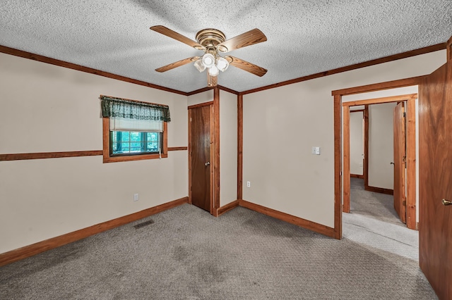 carpeted spare room with visible vents, crown molding, a textured ceiling, and baseboards