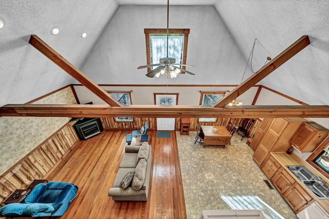 unfurnished living room with vaulted ceiling, a textured ceiling, hardwood / wood-style flooring, and a ceiling fan