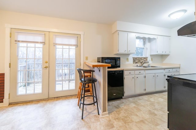 kitchen featuring a breakfast bar, sink, white cabinets, black appliances, and french doors