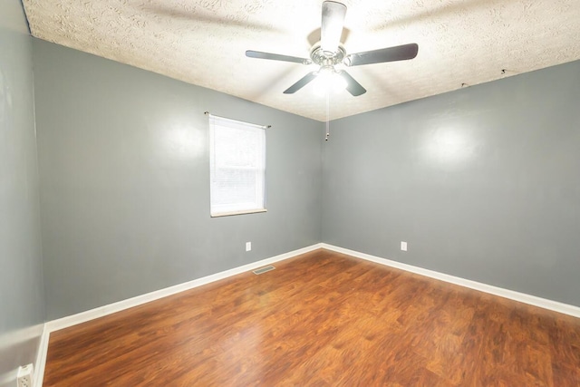 empty room with ceiling fan, wood-type flooring, and a textured ceiling