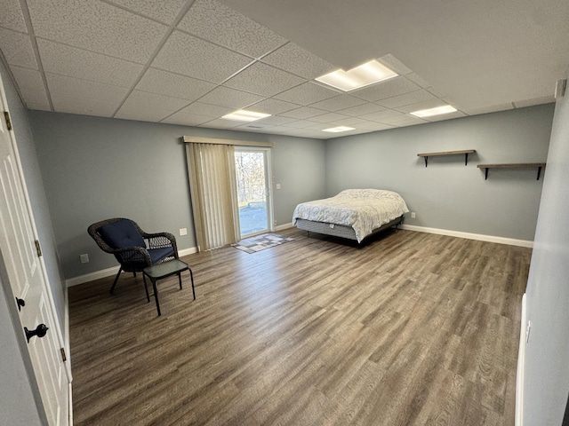 bedroom featuring wood-type flooring, a drop ceiling, and access to exterior