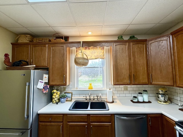 kitchen with stainless steel appliances, sink, a drop ceiling, and decorative backsplash