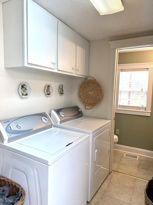 laundry area with light tile patterned flooring, washer and dryer, and a textured ceiling