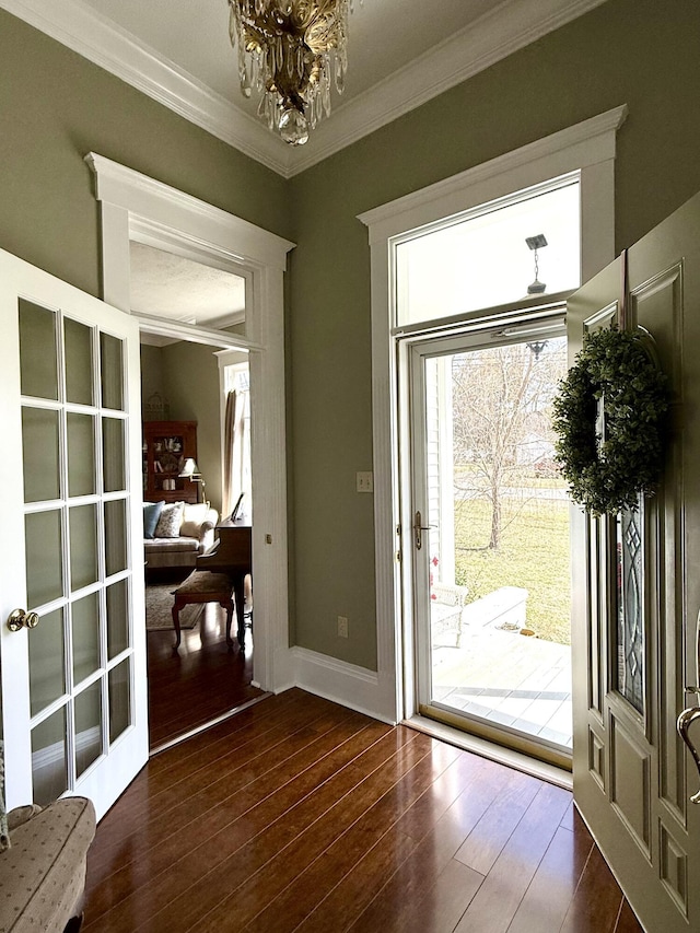 doorway to outside with a notable chandelier, dark wood-type flooring, ornamental molding, and french doors