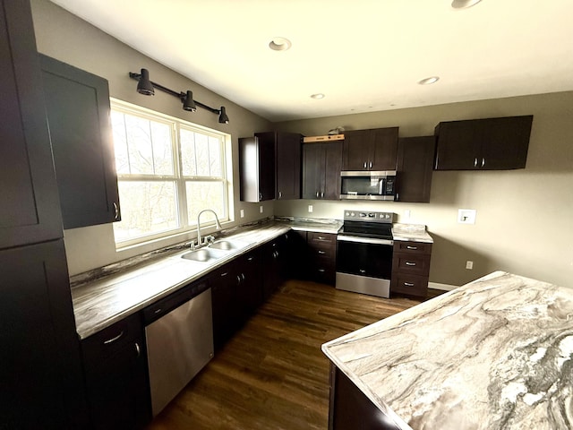 kitchen with dark wood-type flooring, dark brown cabinetry, appliances with stainless steel finishes, and sink