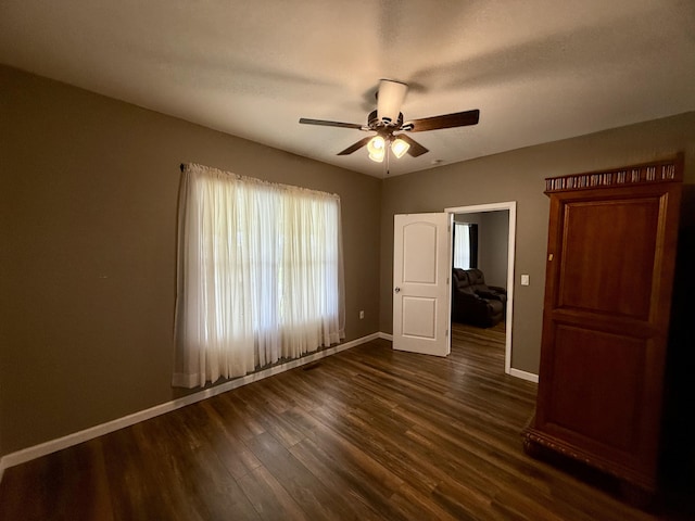 unfurnished bedroom featuring dark wood-type flooring, baseboards, and ceiling fan