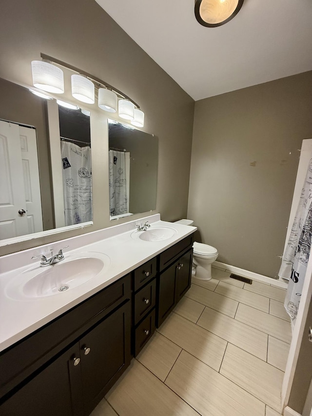 full bathroom with double vanity, toilet, and baseboards