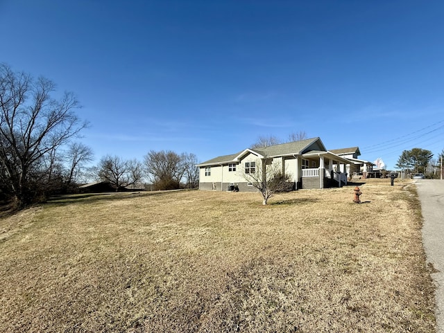 view of side of property featuring covered porch and a yard