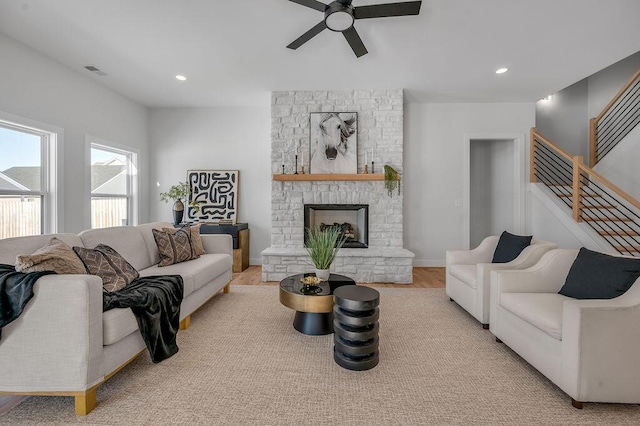 living room featuring ceiling fan, a fireplace, and light wood-type flooring