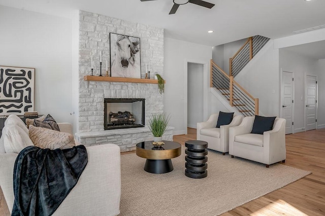 living room with hardwood / wood-style flooring, ceiling fan, and a fireplace