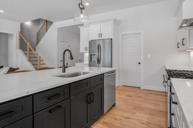 kitchen featuring sink, white cabinets, hanging light fixtures, light hardwood / wood-style floors, and stainless steel appliances