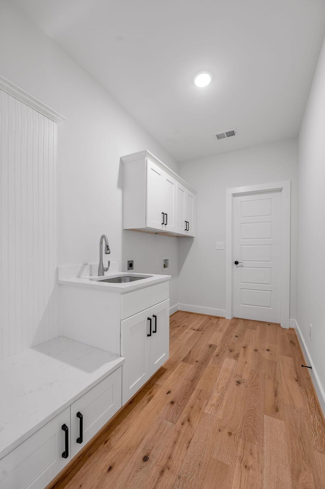 washroom featuring sink, cabinets, hookup for a washing machine, electric dryer hookup, and light wood-type flooring