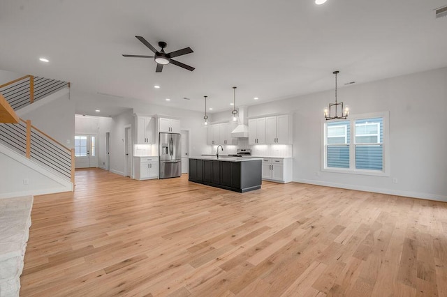 kitchen featuring hanging light fixtures, a kitchen island with sink, white cabinets, and stainless steel fridge with ice dispenser