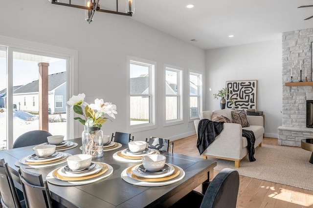 dining space featuring a stone fireplace and light hardwood / wood-style floors