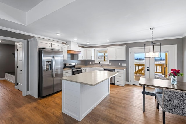 kitchen featuring custom range hood, wood finished floors, stainless steel appliances, light countertops, and white cabinetry