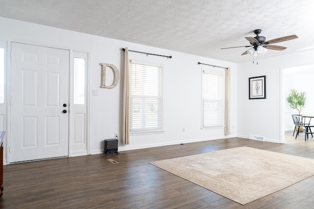 foyer entrance featuring ceiling fan, dark wood-type flooring, and a textured ceiling