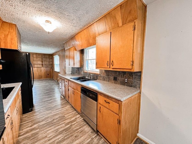 kitchen featuring sink, backsplash, a textured ceiling, stainless steel dishwasher, and light wood-type flooring