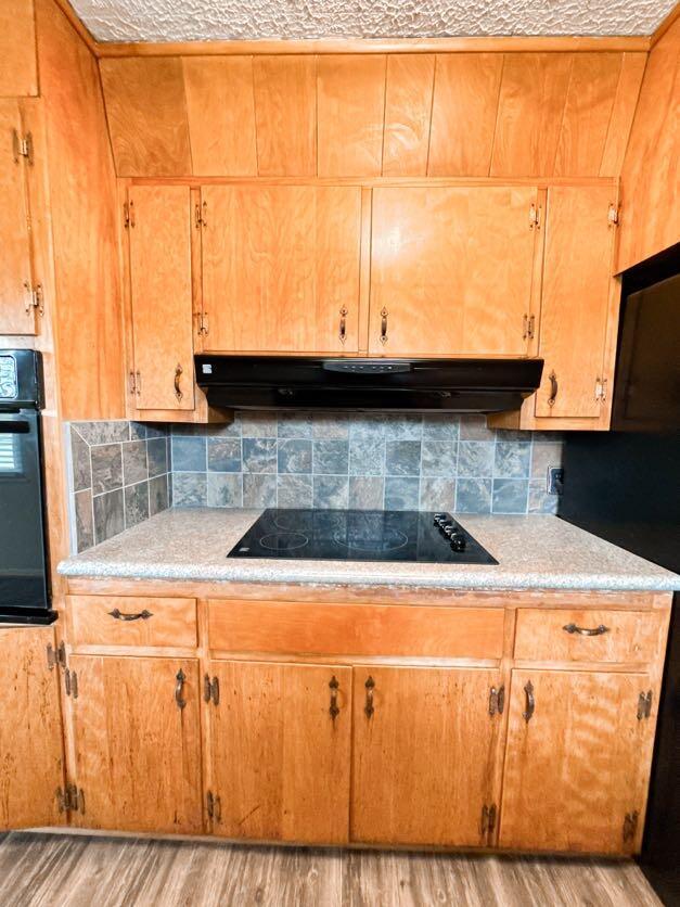 kitchen with decorative backsplash, black appliances, and light wood-type flooring