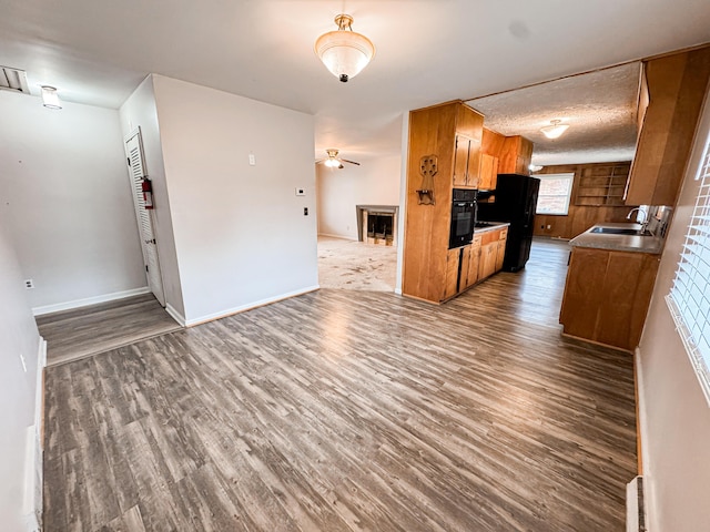 kitchen featuring ceiling fan, wood-type flooring, sink, and black oven