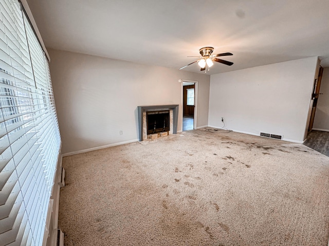 unfurnished living room featuring ceiling fan and carpet