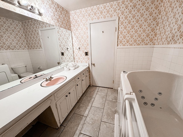 bathroom featuring a tub to relax in, vanity, toilet, and tile walls