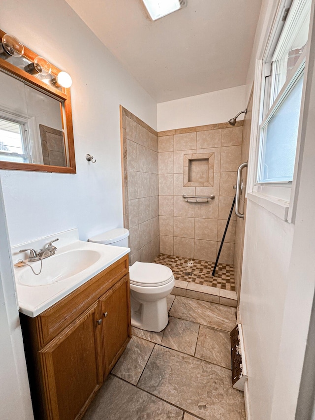 bathroom featuring vanity, toilet, and a tile shower