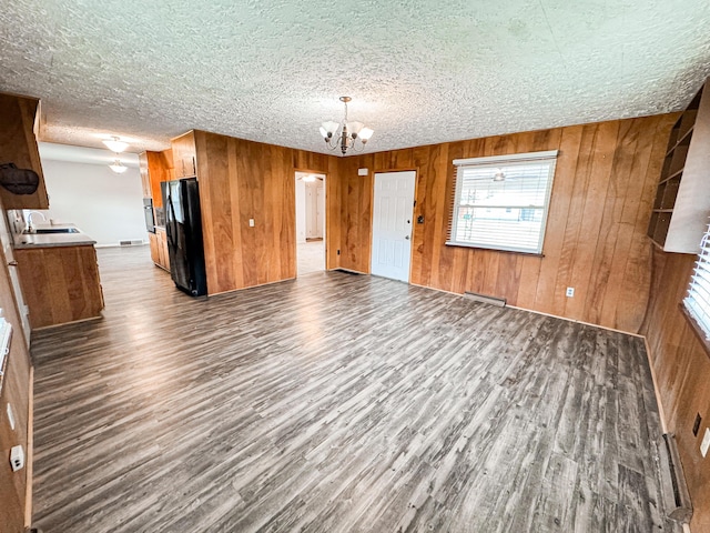 interior space with an inviting chandelier, wooden walls, dark hardwood / wood-style flooring, and a textured ceiling