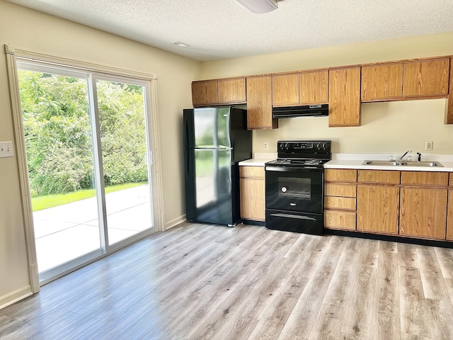 kitchen featuring sink, light hardwood / wood-style floors, black appliances, a textured ceiling, and exhaust hood