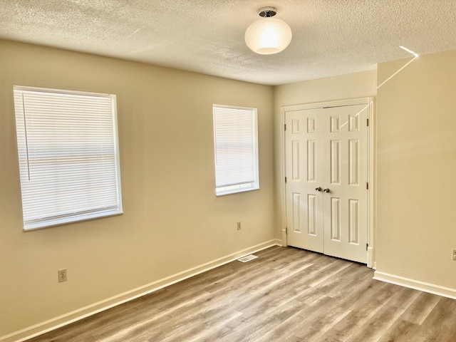 unfurnished bedroom with a closet, a textured ceiling, and light wood-type flooring