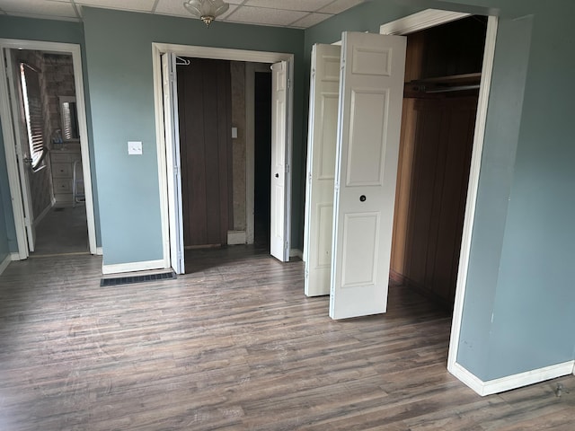 unfurnished bedroom featuring wood-type flooring and a paneled ceiling