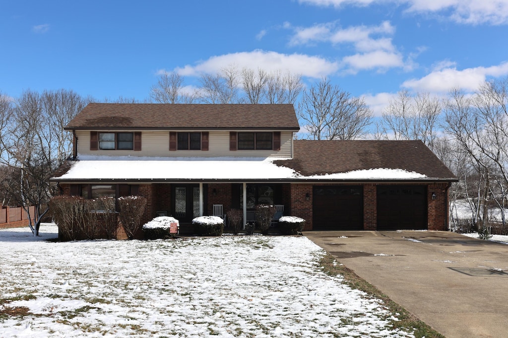 traditional home featuring driveway, brick siding, a porch, and an attached garage