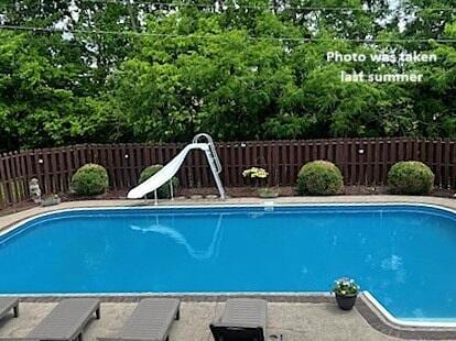 view of pool with a water slide and fence