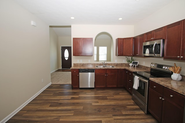 kitchen featuring dark wood-type flooring, appliances with stainless steel finishes, stone countertops, and sink