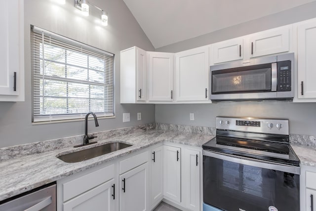 kitchen featuring lofted ceiling, stainless steel appliances, a sink, and white cabinets